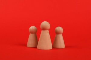 A red background with 3 wooden people abstract figures
